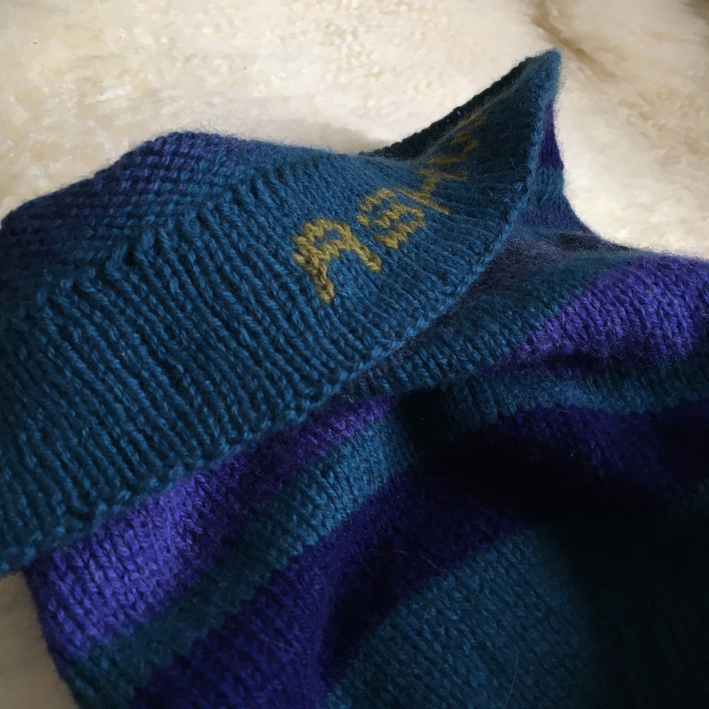 Hem of a handknit hat, with the name knit into the hem.