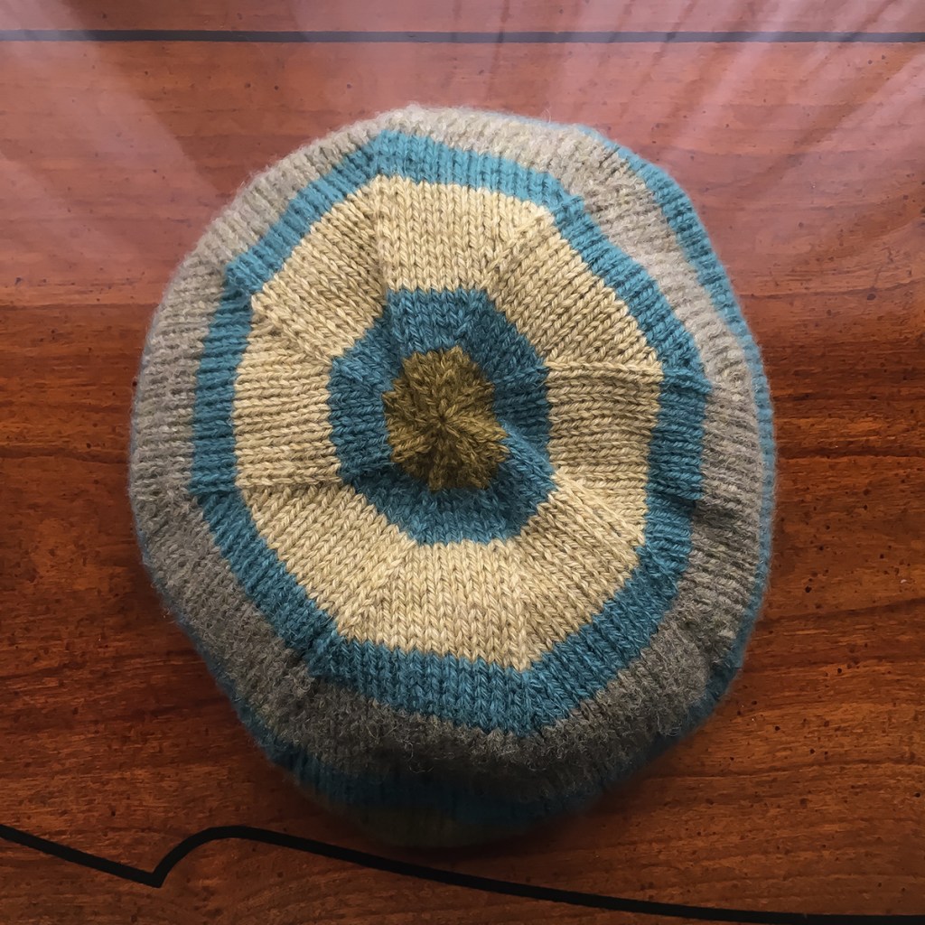The crown of a striped, handknit hat.