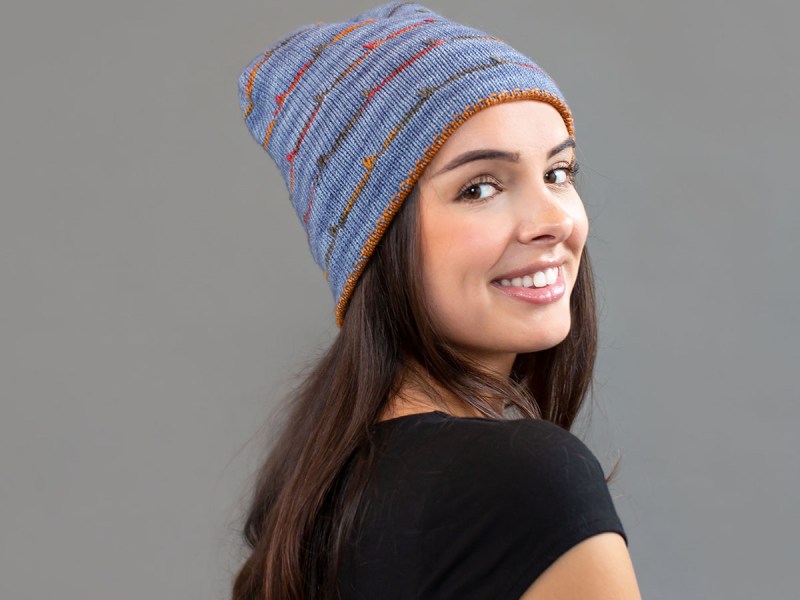 Woman wearing a blue hat with multicolour stripes.