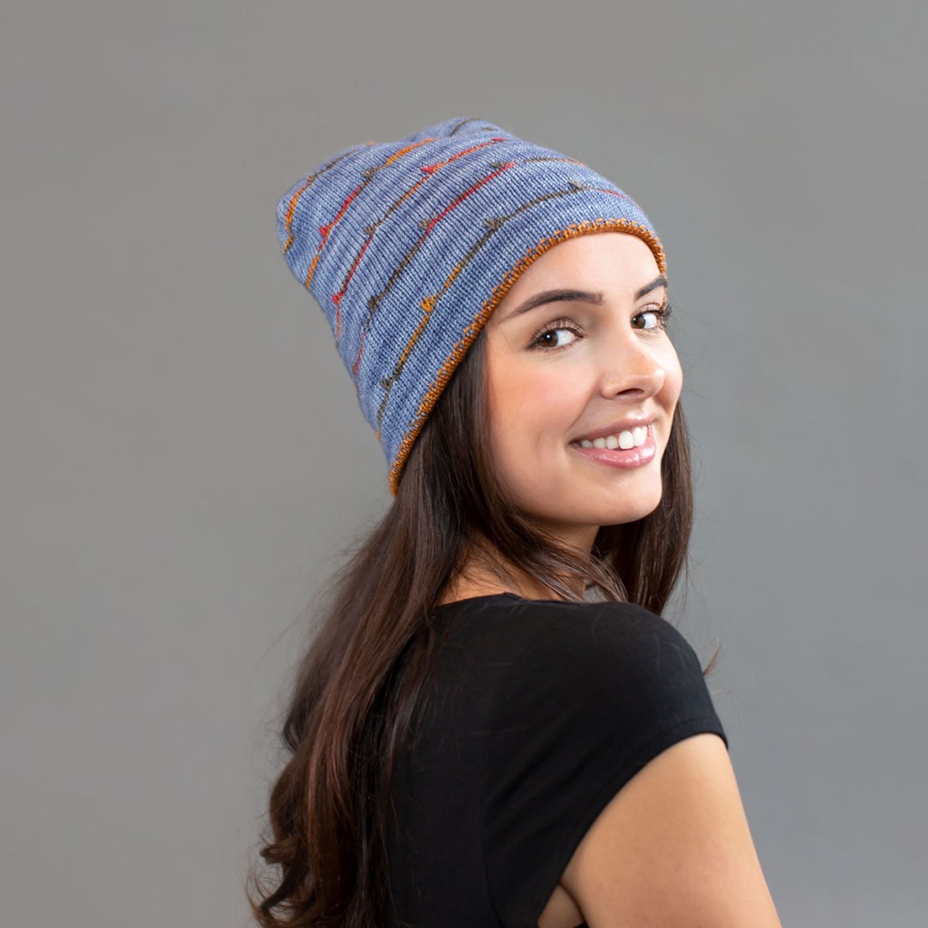 Woman wearing a blue hat with multicolour stripes.
