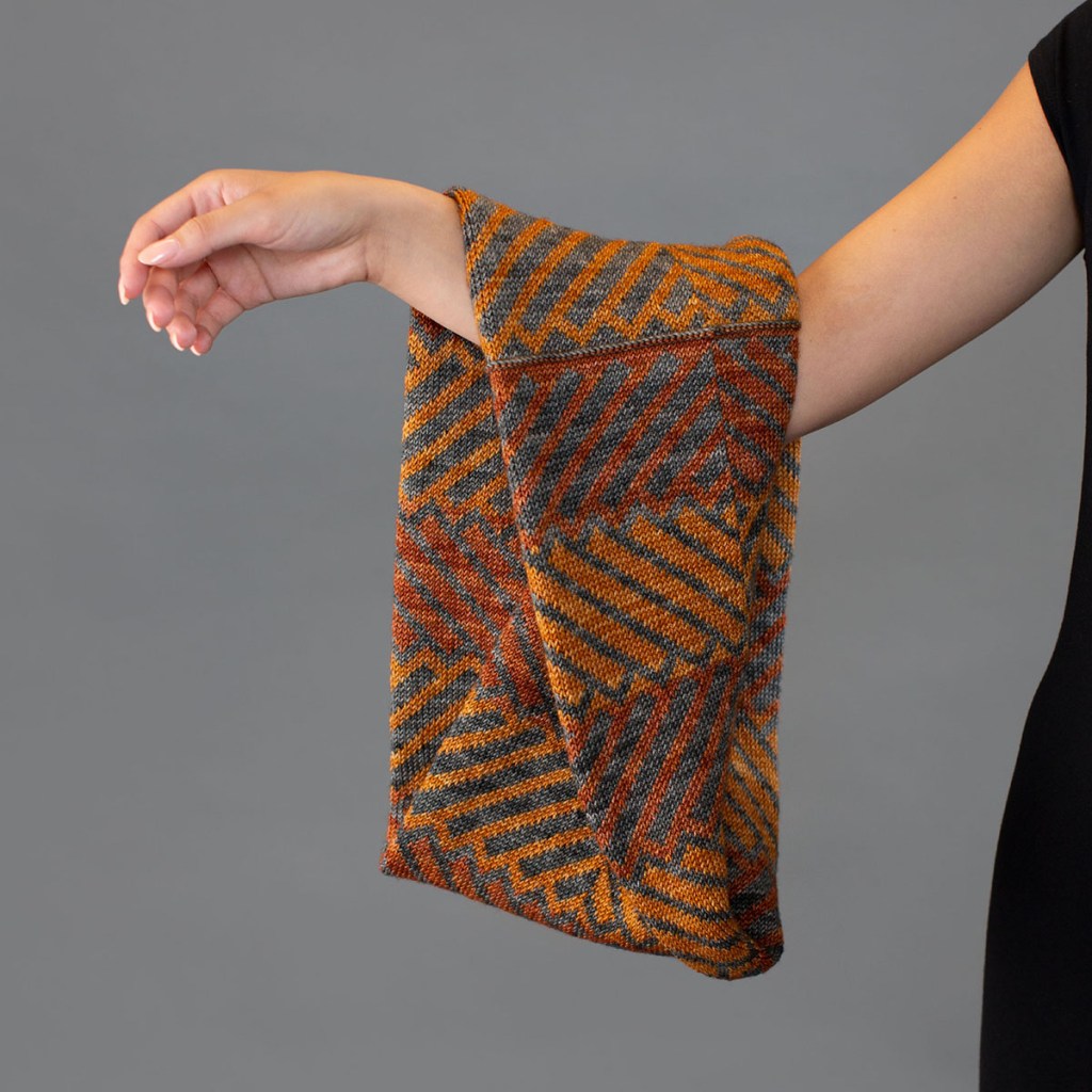 Hand knit colourwork cowl hanging from a woman's arm.