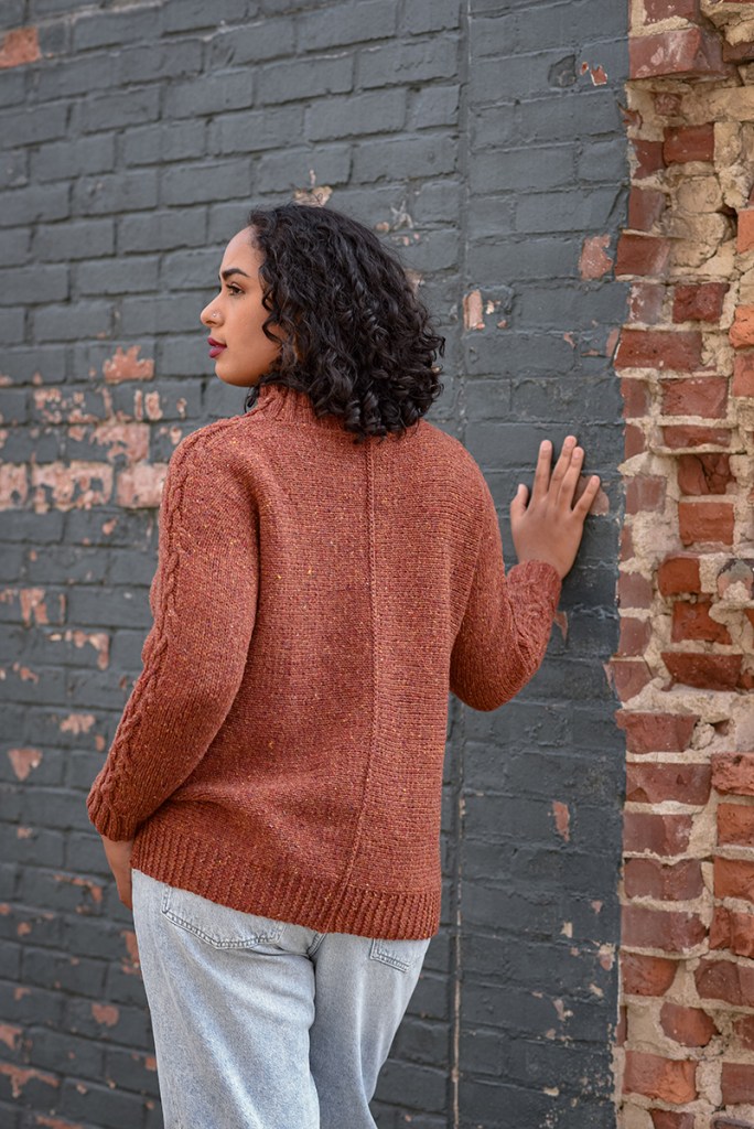 Back view of a woman wearing a hand knit pullover.