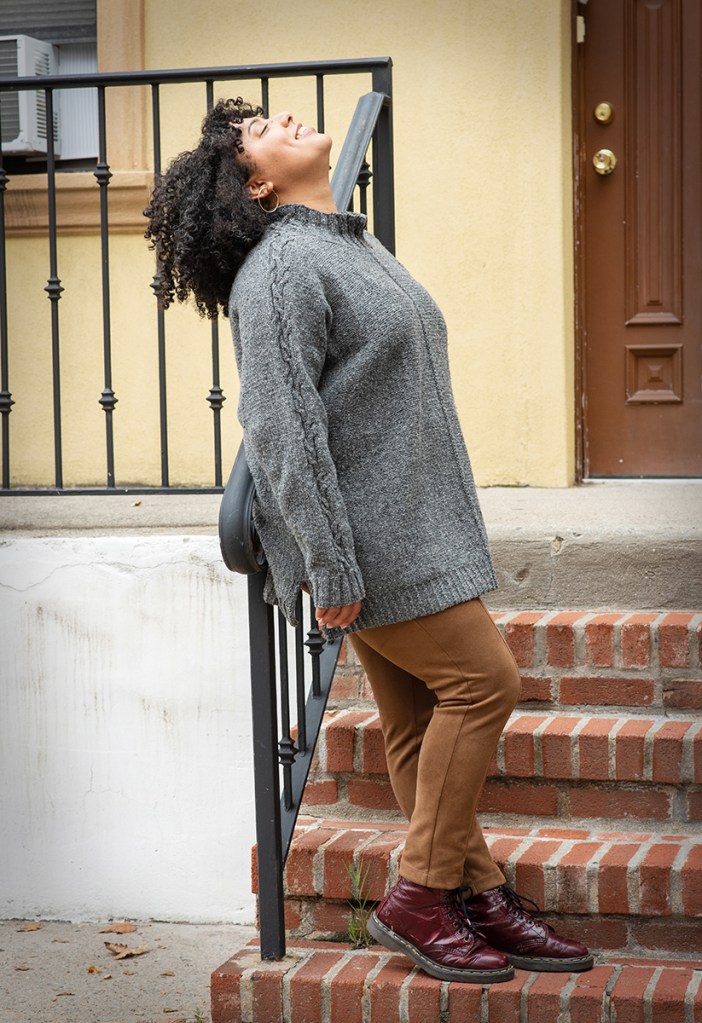 Side view of a woman wearing a hand knit pullover.