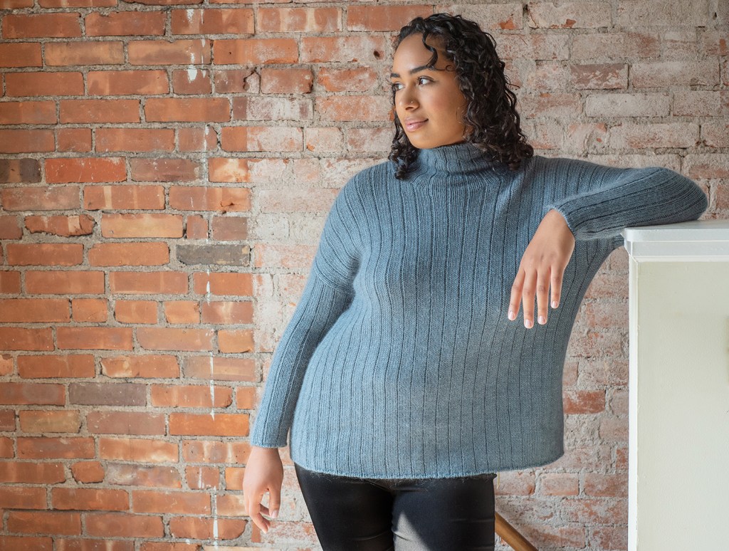 Maple Bay front view, model leaning left with her arm up. This shows the underarm shaping and the ease.