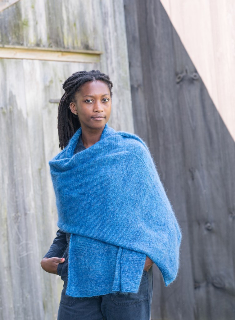 A woman wearing the Departure Bay shawl wrapped around her, one end thrown over her left shoulder and covering her arm.