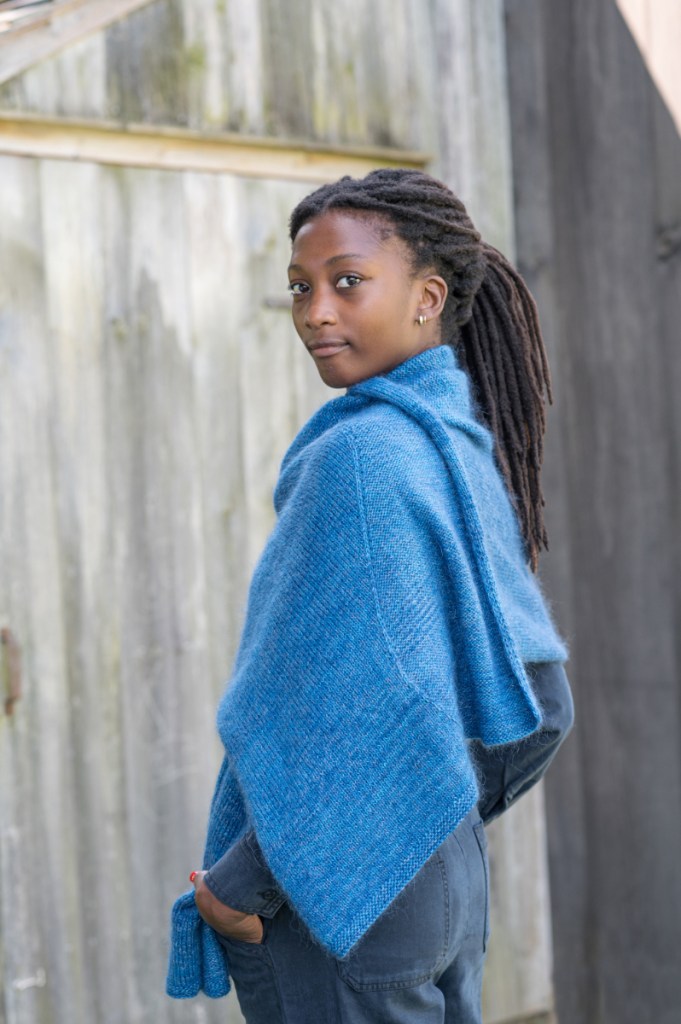 A woman in the Departure Bay shawl, with one end thrown over her shoulder, seen from the side. She is looking at the camera.